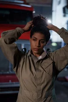 Portrait of a confident mechanic woman adjusting her hair in a garage.