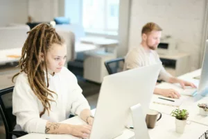 Two colleagues concentrating on work, using computers in a bright modern office.