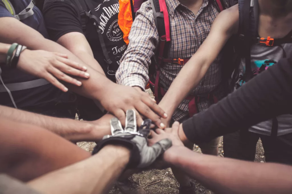 A group of diverse individuals join hands for teamwork in West Java, Indonesia.