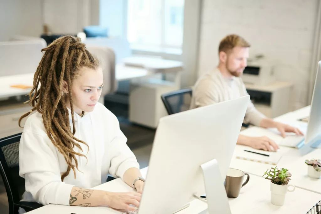Deux collègues concentrés sur leur ordinateur dans un bureau lumineux