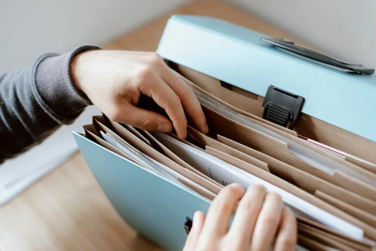 Mains classant des documents dans un dossier bleu
