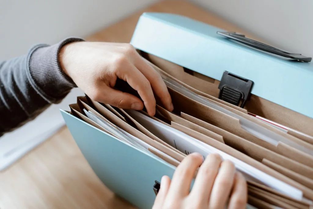 Mains classant des documents dans un dossier bleu